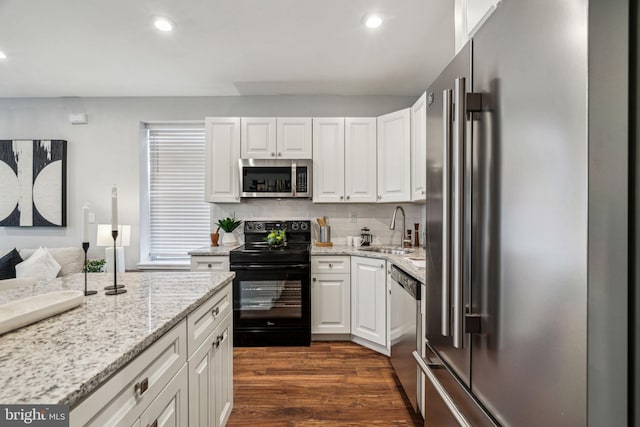 kitchen with sink, stainless steel appliances, dark hardwood / wood-style floors, light stone countertops, and white cabinets