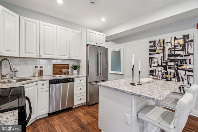 kitchen with appliances with stainless steel finishes, sink, a breakfast bar area, and white cabinets