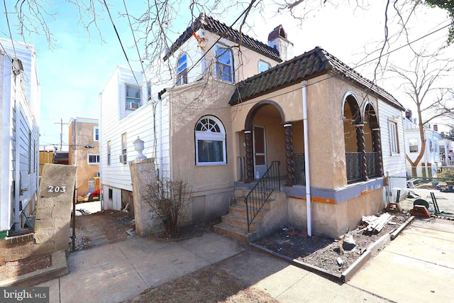 view of front of home featuring a chimney, fence, and stucco siding