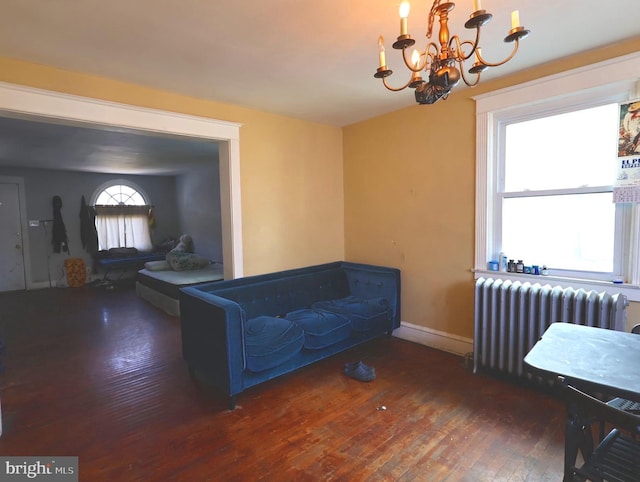 living area featuring a chandelier, dark wood-type flooring, radiator heating unit, and baseboards