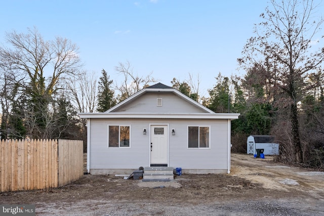 bungalow-style house featuring entry steps, a storage shed, fence, and an outdoor structure