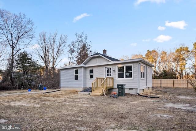 rear view of house featuring crawl space, a chimney, and fence