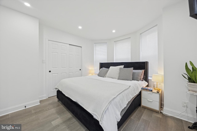 bedroom with light wood-type flooring, a closet, baseboards, and recessed lighting