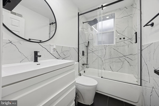 full bath featuring toilet, combined bath / shower with glass door, vanity, and tile walls