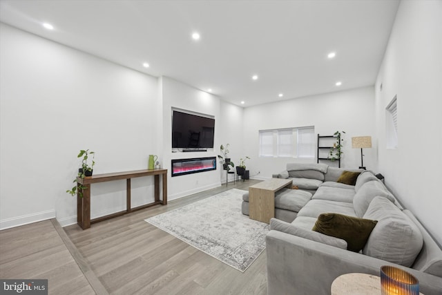 living room with baseboards, recessed lighting, a glass covered fireplace, and light wood-style floors