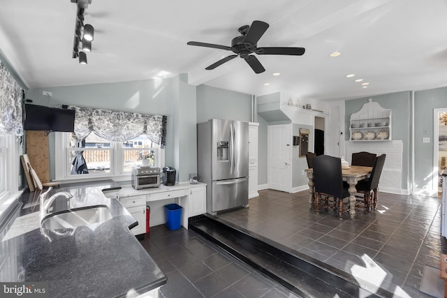 kitchen with stainless steel fridge with ice dispenser, vaulted ceiling, a sink, dark tile patterned flooring, and baseboards