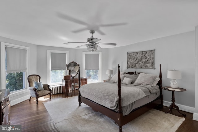 bedroom featuring a ceiling fan, radiator, baseboards, and wood finished floors