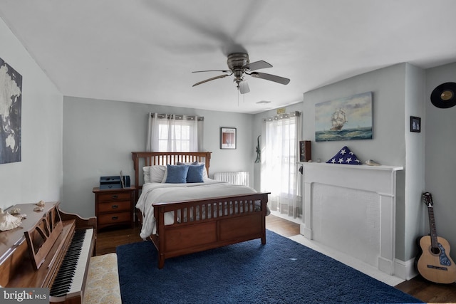 bedroom with ceiling fan, multiple windows, wood finished floors, and radiator