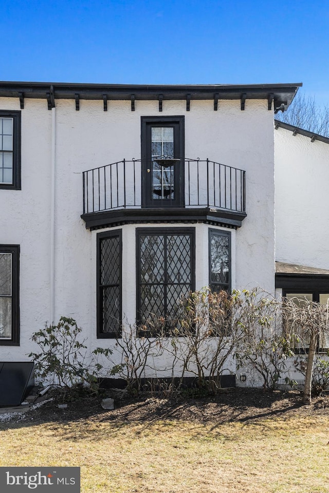 rear view of property featuring a balcony and stucco siding