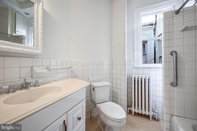 full bathroom with toilet, radiator heating unit, tile patterned flooring, vanity, and tile walls