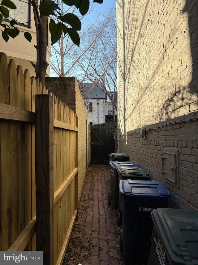 view of property exterior with a gate, fence, and brick siding