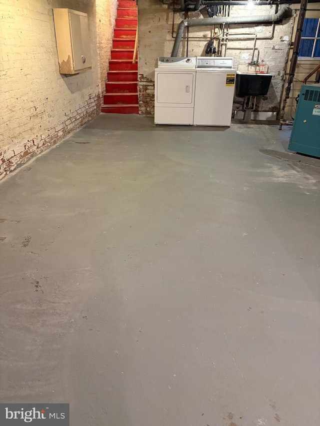 unfinished basement featuring washing machine and dryer, a heating unit, and a sink