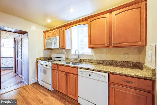 kitchen featuring tasteful backsplash, sink, light stone counters, light hardwood / wood-style floors, and white appliances