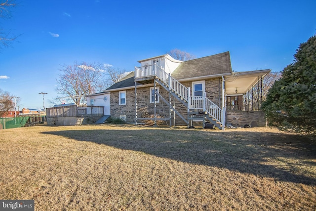 rear view of property featuring a wooden deck and a lawn