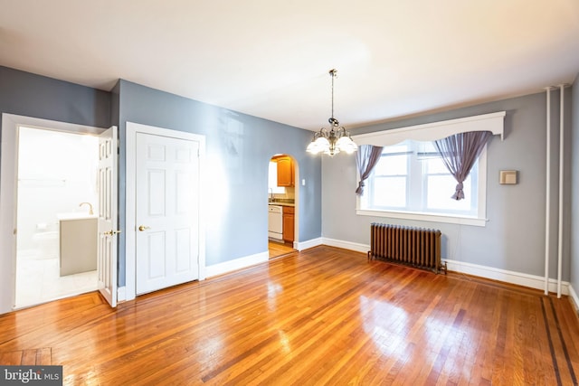 unfurnished dining area featuring hardwood / wood-style floors, radiator heating unit, and a chandelier