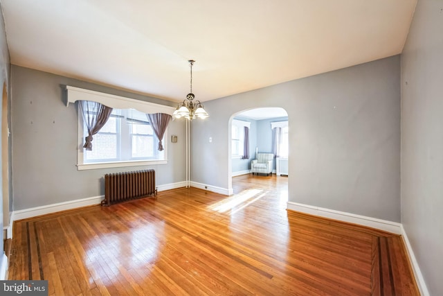 unfurnished dining area featuring radiator heating unit and wood-type flooring