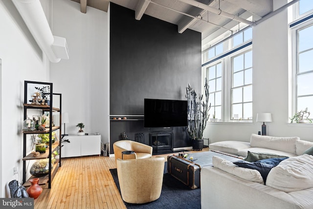 living room with plenty of natural light, beam ceiling, hardwood / wood-style floors, and a high ceiling