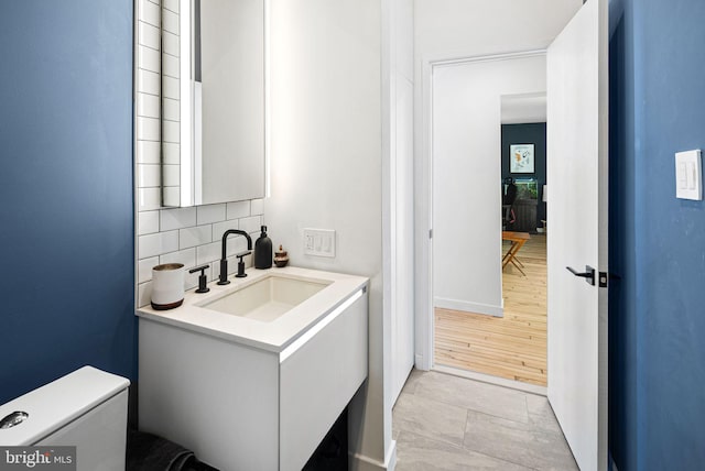 bathroom featuring vanity, backsplash, and toilet