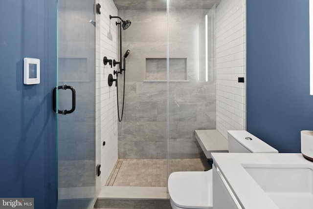 bathroom featuring vanity, a shower with shower door, and toilet