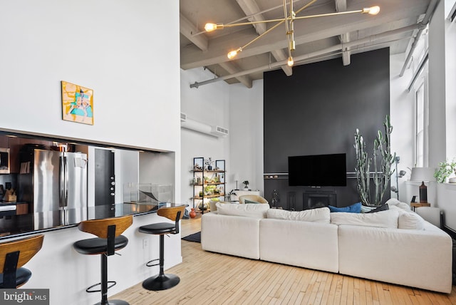 living room featuring beam ceiling, high vaulted ceiling, and light hardwood / wood-style flooring