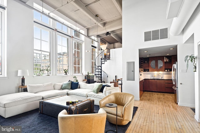 living room with sink, hardwood / wood-style flooring, electric panel, and a towering ceiling