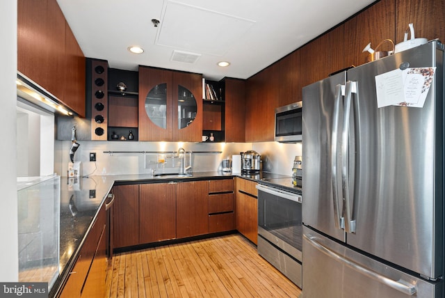 kitchen with backsplash, stainless steel appliances, sink, and light wood-type flooring