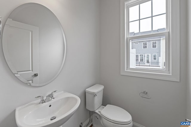 bathroom featuring toilet, sink, and a wealth of natural light