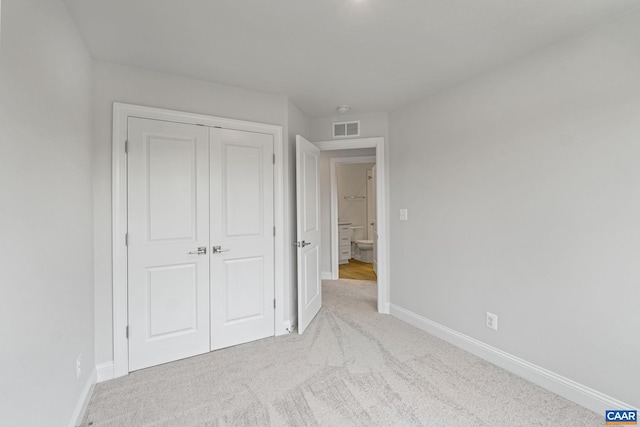 unfurnished bedroom with light carpet and a closet