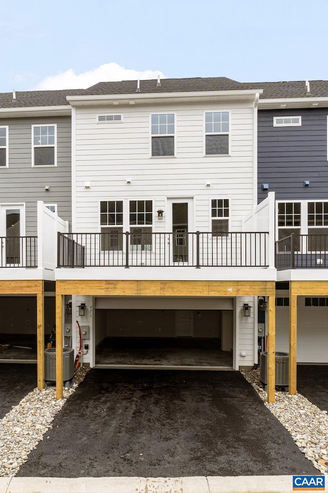 rear view of property featuring central AC and a garage