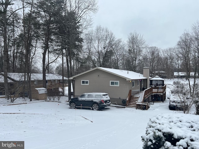 snow covered property featuring a chimney and a deck