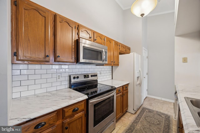 kitchen featuring appliances with stainless steel finishes, a towering ceiling, backsplash, ornamental molding, and light stone countertops