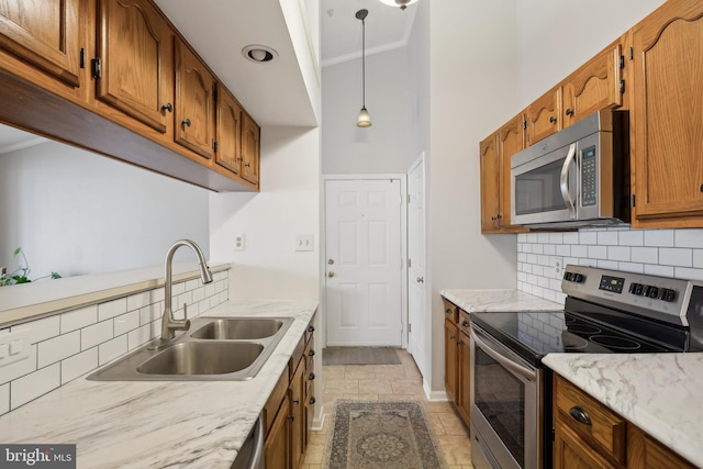 kitchen with sink, crown molding, hanging light fixtures, stainless steel appliances, and decorative backsplash