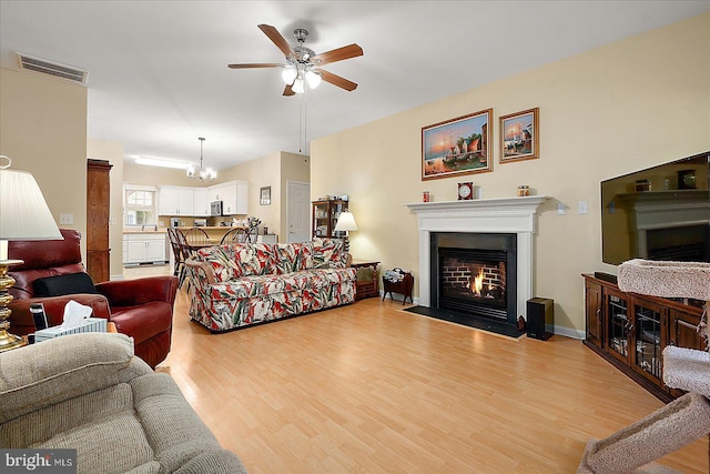 living room featuring ceiling fan with notable chandelier and light hardwood / wood-style flooring