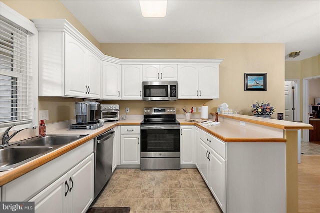 kitchen featuring appliances with stainless steel finishes, kitchen peninsula, sink, and white cabinets