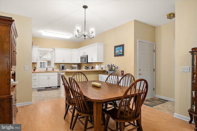 dining room with a chandelier, sink, and light hardwood / wood-style flooring