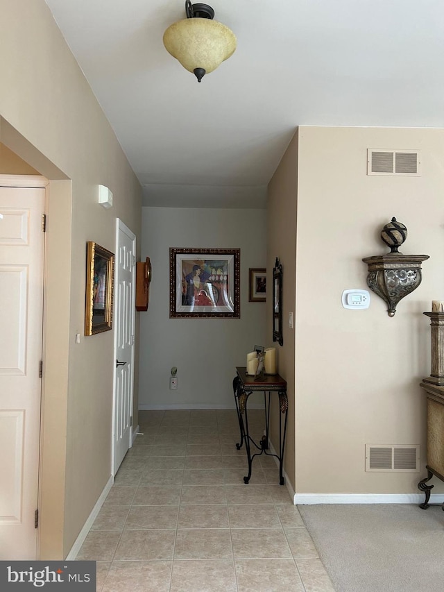 corridor featuring light tile patterned flooring, visible vents, and baseboards