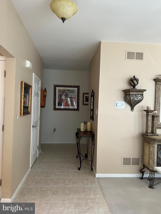 hallway featuring light tile patterned floors, visible vents, and baseboards