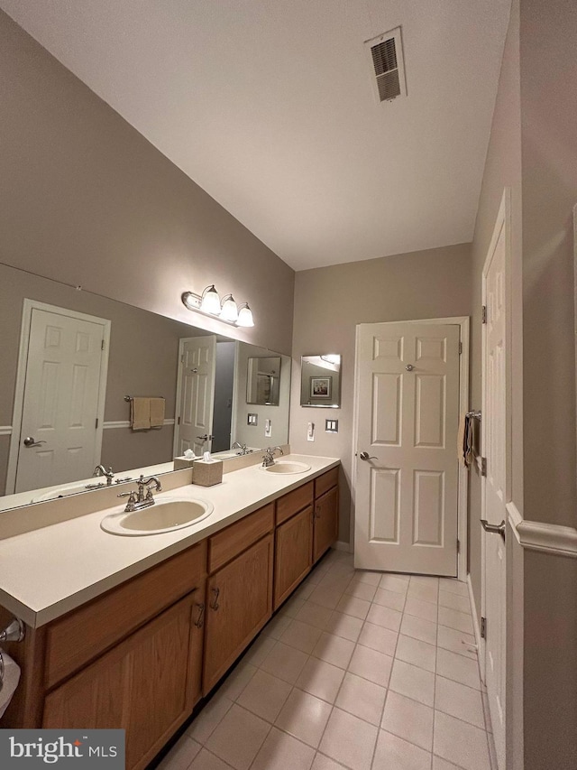 bathroom with double vanity, a sink, visible vents, and tile patterned floors