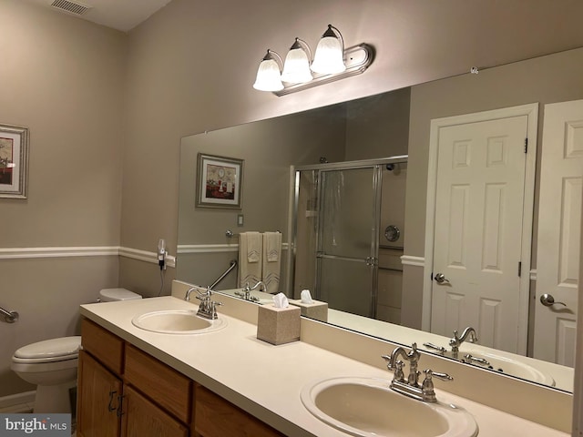 bathroom featuring a sink, a shower stall, toilet, and double vanity