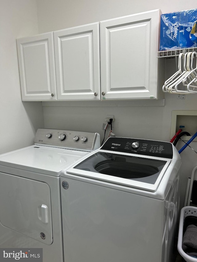 clothes washing area with cabinet space and washer and dryer