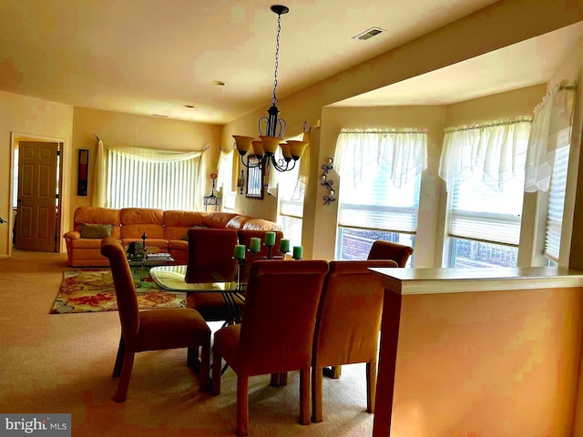 carpeted dining space with visible vents and an inviting chandelier