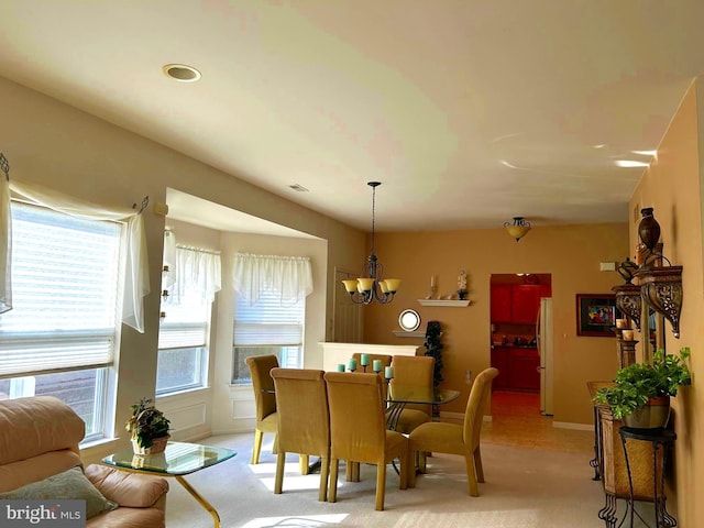 dining space featuring baseboards, a chandelier, and light colored carpet