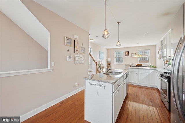 kitchen featuring appliances with stainless steel finishes, light hardwood / wood-style flooring, a kitchen island, and white cabinets