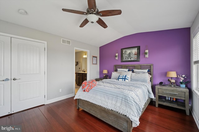 bedroom featuring vaulted ceiling, ensuite bathroom, dark hardwood / wood-style floors, ceiling fan, and a closet