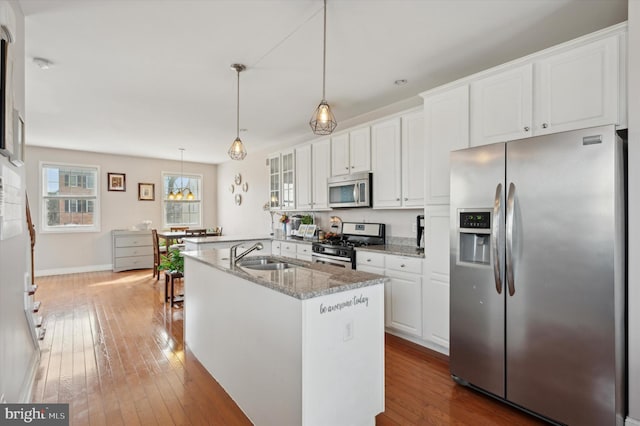 kitchen featuring light stone countertops, white cabinetry, appliances with stainless steel finishes, and pendant lighting