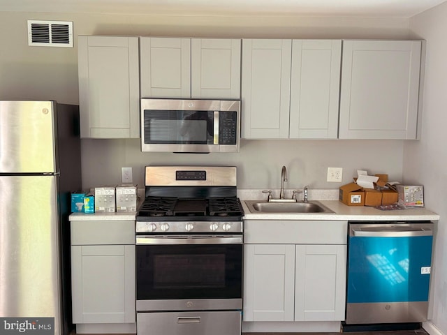 kitchen with stainless steel appliances, sink, and white cabinets