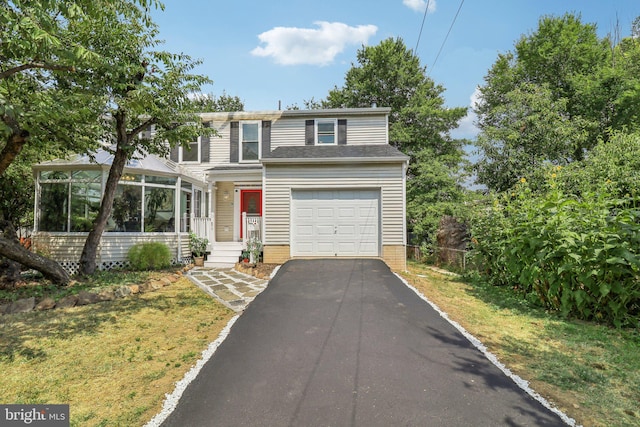 view of front property with a garage, a front lawn, and a sunroom