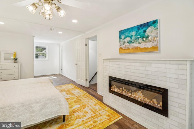 bedroom with a brick fireplace, dark wood-type flooring, and ornamental molding