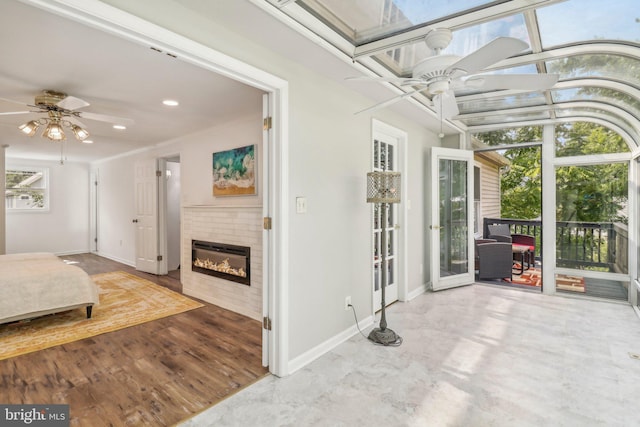 unfurnished sunroom with a tiled fireplace and ceiling fan