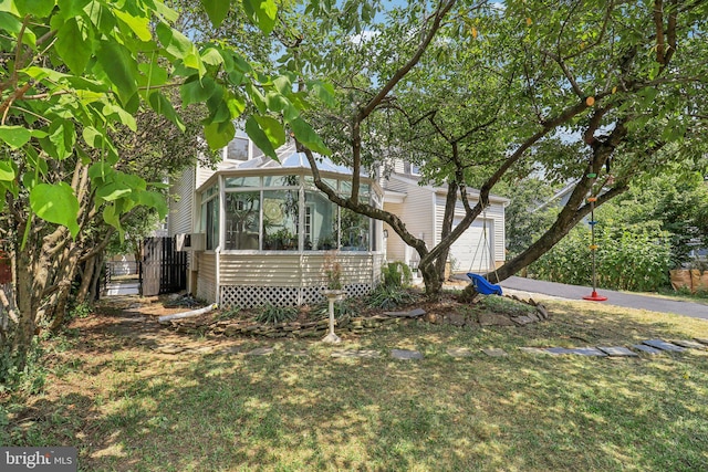 view of side of home with a garage, a yard, and a sunroom